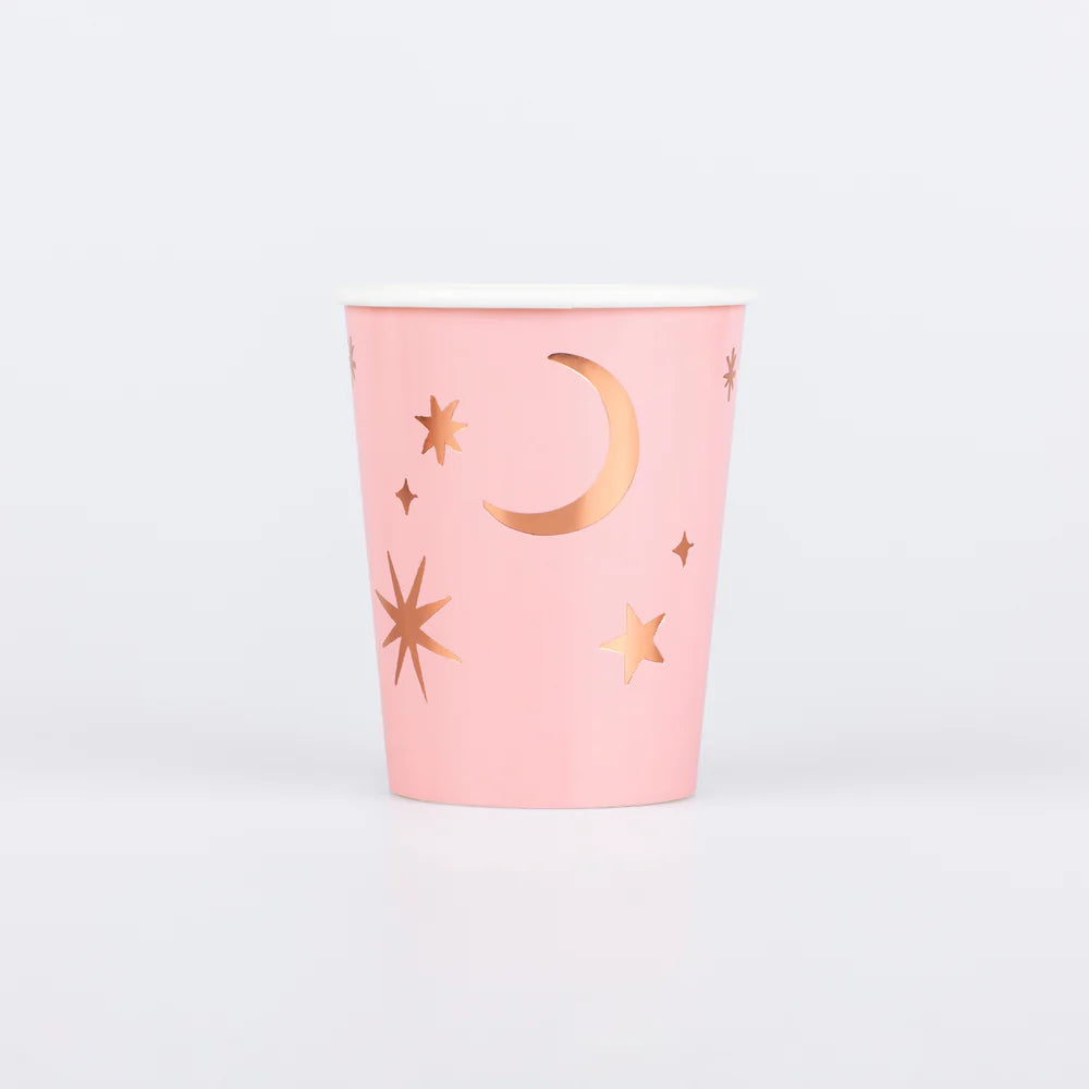 Pink cup with gold star and moon designs on a light gray background