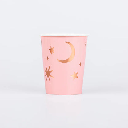 Pink cup with gold star and moon designs on a light gray background