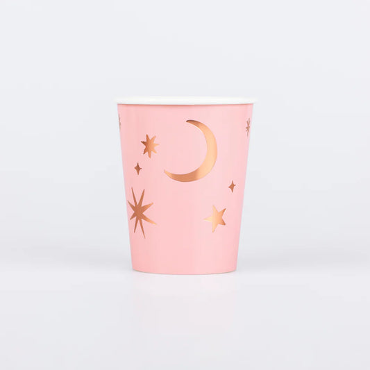 Pink cup with gold star and moon designs on a light gray background